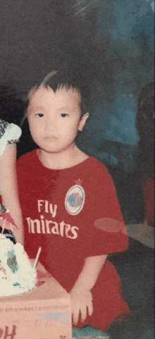 a young boy wearing a fly emirates shirt