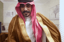 a man wearing a keffiyeh and a robe is smiling