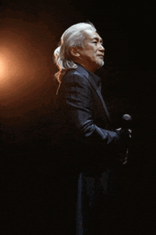 a man with long white hair and a beard is smiling with his arms crossed .