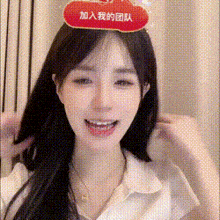 a woman wearing a white shirt and a red hat with chinese writing on it is smiling .