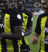 a group of soccer players wearing black and yellow jerseys with the letters ylhlh on the shorts