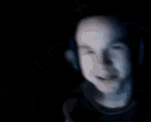 a man is taking off his shirt in a dark room with a microphone .