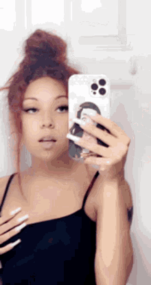 a woman is taking a selfie in front of a mirror .