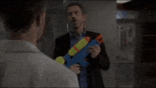 a man in a suit is holding a blue water gun
