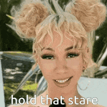 a woman with blonde hair in buns is smiling and says hold that stare .