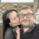 a woman kisses a man on the cheek while they pose for a picture