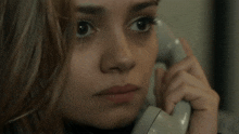 a close up of a woman talking on a white phone