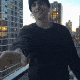 a man wearing a black hat and a purple sweater is reaching out his hand