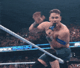 a shirtless wrestler is holding a microphone in front of a banner that says smackdown