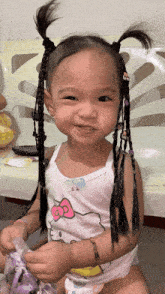 a little girl wearing a hello kitty tank top smiles at the camera