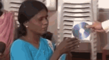 a woman in a blue shirt is holding a blue cd in her hands .
