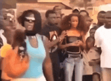 a group of people standing in a line with one woman wearing a blue tank top