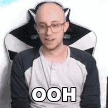 a bald man wearing glasses and headphones is sitting in a chair and smiling .
