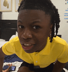 a young boy wearing a yellow shirt is looking at the camera