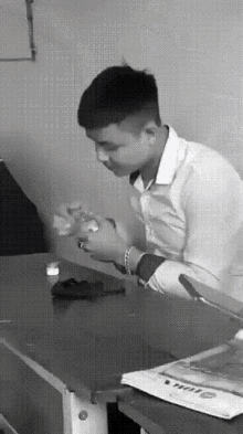a black and white photo of a man sitting at a desk with a phone on it