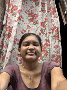 a woman taking a selfie in front of a curtain with flowers on it