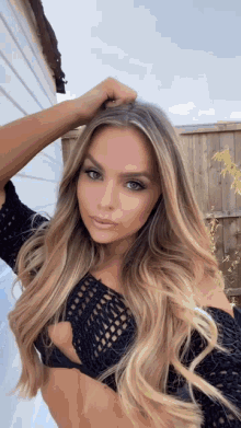 a woman with long blonde hair is taking a selfie in front of a wooden fence