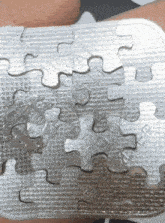 a person is holding a silver puzzle in their hand and the puzzle has the word maker on it