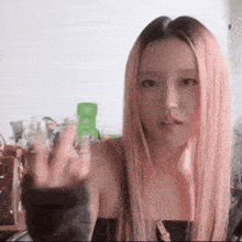a woman with long pink hair is holding a bottle of perfume