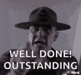 a man wearing a hat is pointing at the camera and saying `` well done ! outstanding '' .