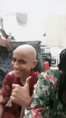 a girl with a shaved head is giving a thumbs up