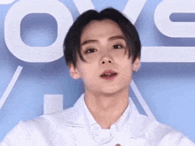 a young man wearing a white shirt is standing in front of a sign that says ' love '