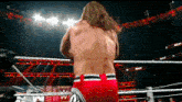 a wrestler stands in a wrestling ring with a sign that says ' ram ' on it