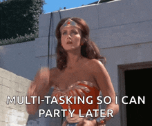 wonder woman says " multi-tasking so i can party later " while standing in front of a building