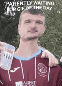 a man in a albert shirt is holding a plastic cup