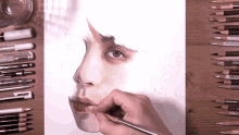 a person drawing a woman 's face with prismacolor pencils in the background