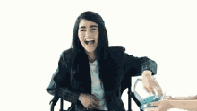 a woman in a wheelchair is laughing while holding a bowl of water .