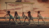 a group of girls are dancing in front of a bus stop at sunset