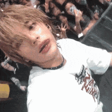 a person wearing a white t-shirt that says ' nirvana ' on it stands in front of a crowd