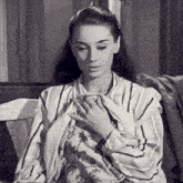 a woman in a striped shirt is sitting on a bench with her hands on her chest