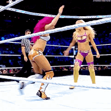two women are wrestling in a ring with a referee in the background .