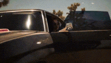 a person is sitting in a car with their door open .