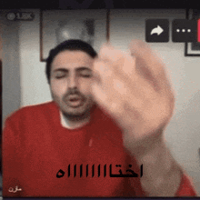a man in a red sweater is giving the middle finger in arabic