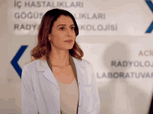 a woman in a lab coat stands in front of a sign that says aci radyoloji laboratuvar