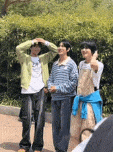 three young men are standing next to each other in front of a bamboo wall .