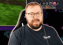 a man wearing glasses and a shirt that says extralife sits in front of a computer screen