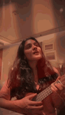 a woman is singing and playing a guitar