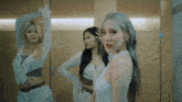 three women are standing in front of a mirror in a room