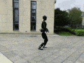 a black robot is walking on a brick sidewalk in front of a building