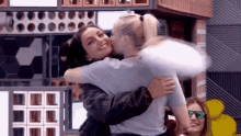 two women are hugging each other in a room .