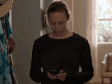 a woman in a black shirt is using her phone