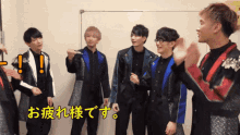 a group of young men are standing next to each other with a sign that says " お疲れ様 です " on it