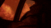a man is standing in front of a fire in a dark room