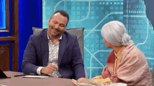 a man and a woman are sitting at a table and smiling