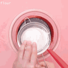 a person is sifting flour into a bowl of red liquid