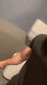 a man in a black shirt is standing in a bathroom next to a toilet